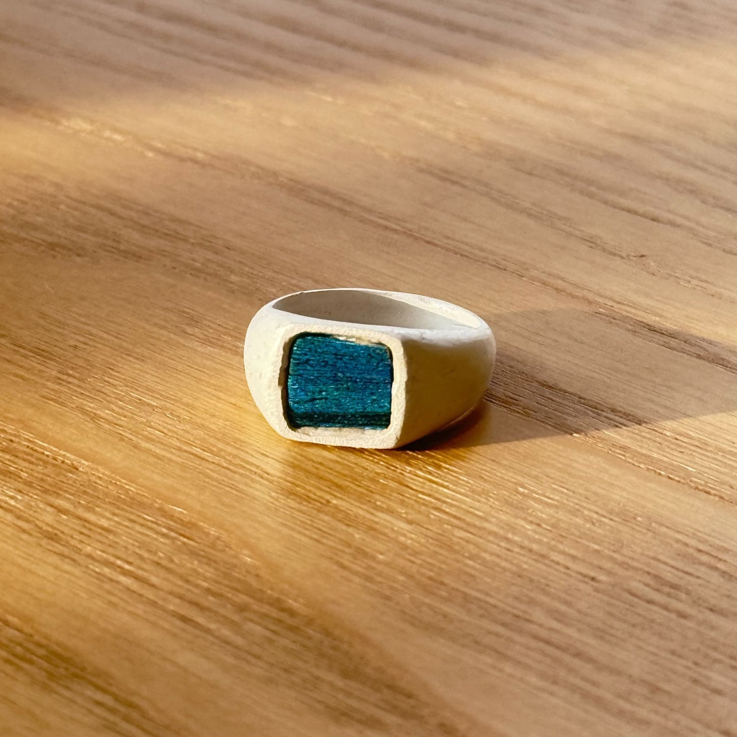 Artisan silver ring with a naturally iridescent peacock feather shimmering in emerald green under the sunset, by Cici Dream.