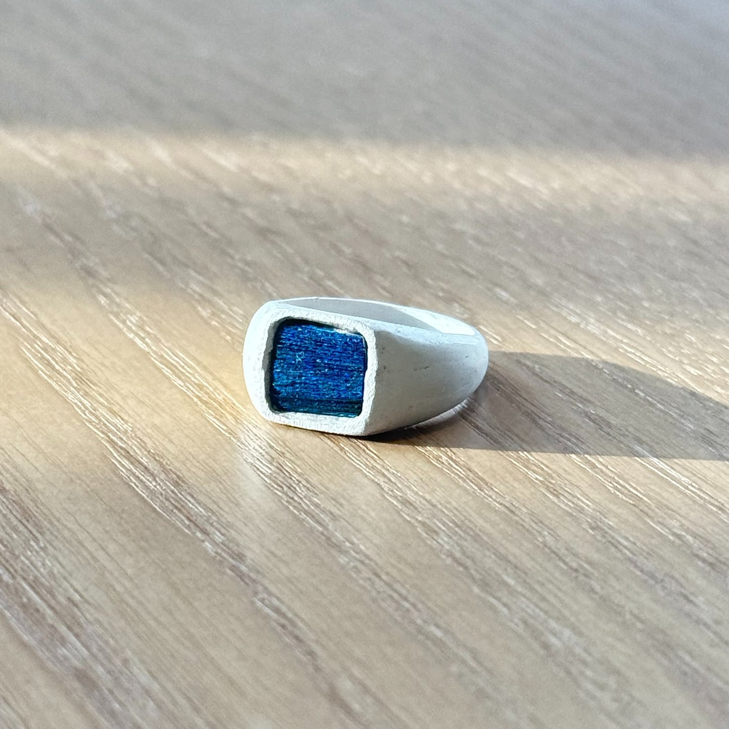 Artisan silver ring featuring a naturally iridescent peacock feather in deeper royal blue tones, by Cici Dream