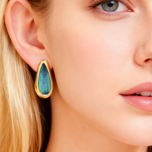 Close-up of a woman wearing Elara Teardrop Shaped Peacock Feather Earrings from Cici Dream