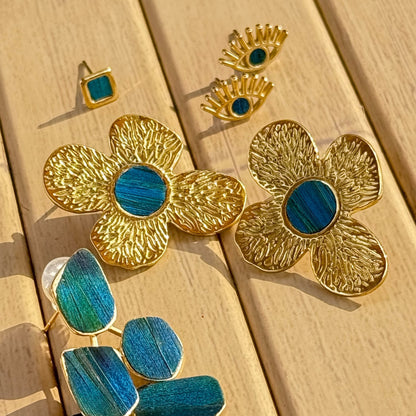 Gold and peacock feather blue floral jewelry set from Cici Dream on a wooden surface