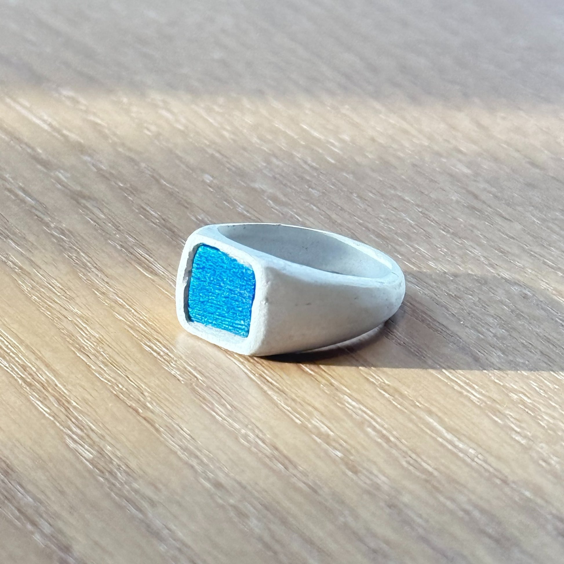 Artisan silver ring featuring a naturally iridescent peacock feather shifting from bright teal to royal blue, by Cici Dream