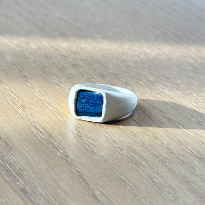 Artisan silver ring featuring a naturally iridescent peacock feather in deeper royal blue tones, by Cici Dream